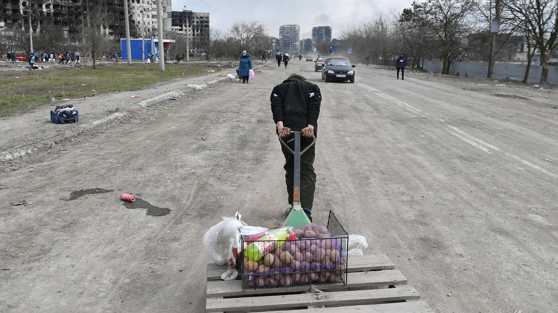 Мужчина везет тележку с продуктами на дороге в Мариуполе - РИА Новости, 1920, 22.03.2022
