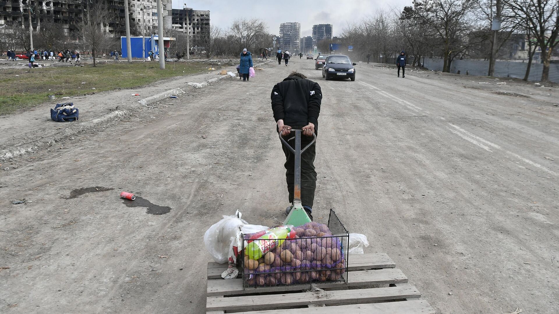 Мужчина везет тележку с продуктами на дороге в Мариуполе - РИА Новости, 1920, 17.03.2022