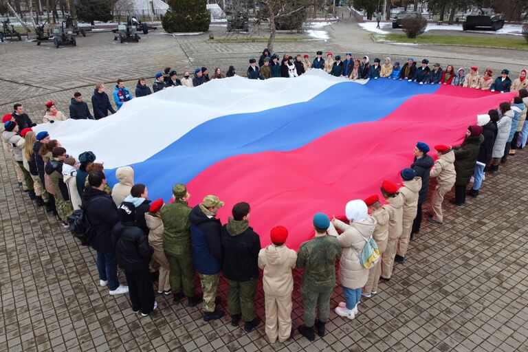 Представители молодежных общественных организаций развернули государственный флаг России в честь празднования Дня воссоединения Крыма с Россией у Выставочного зала Боевой славы в Краснодаре