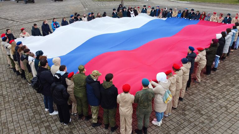 Представители молодежных общественных организаций развернули государственный флаг России в честь празднования Дня воссоединения Крыма с Россией у Выставочного зала Боевой славы в Краснодаре