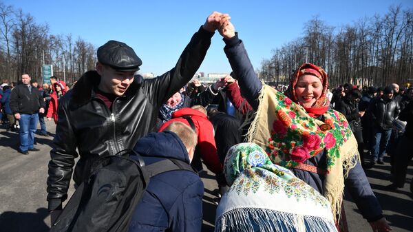 Люди играют в Ручеек у большой спортивной арены Лужники в Москве перед началом митинга-концерта, посвященного воссоединению Крыма с Россией