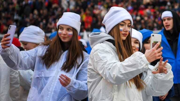 Девушки фотографируются на стадионе Лужники перед началом митинга-концерта, посвященного воссоединению Крыма с Россией