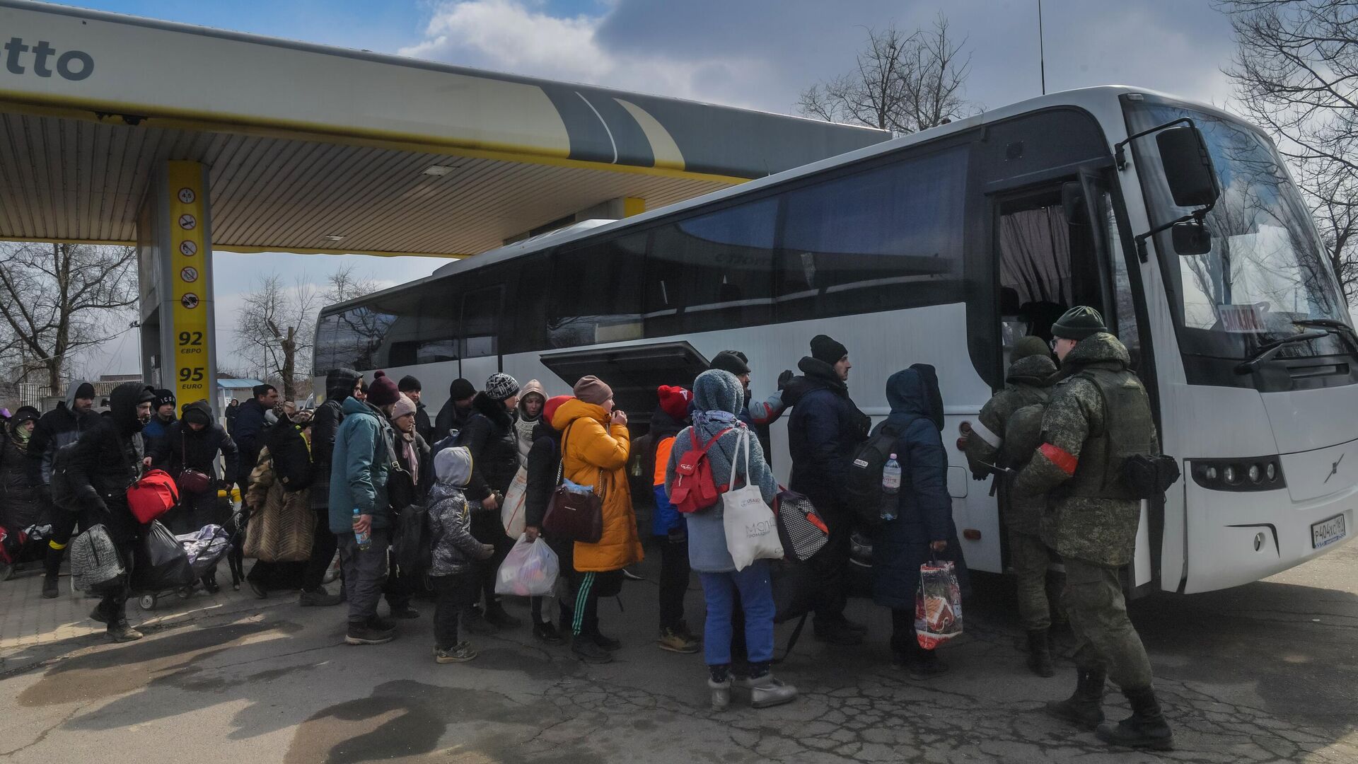 Беженцы готовятся к посадке в автобус на Запорожском шоссе в Мариуполе - РИА Новости, 1920, 20.03.2022