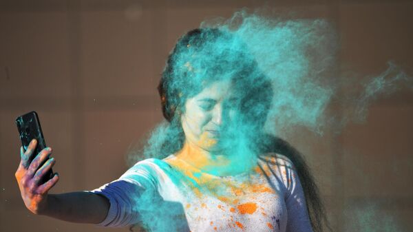 Девушки делает селфи во время обсыпания краской на фестивале индийской культуры Холи Мела в Москве