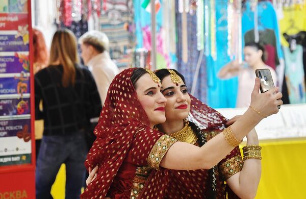 Девушки в традиционной индийской одежде фотографируются на индийском базаре на фестивале Холи Мела в Москве