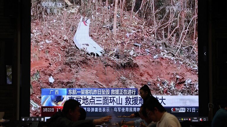 Обломки самолета Boeing 737-800 авиакомпании China Eastern Airlines на экране телевизора в ресторане в Пекине, Китай