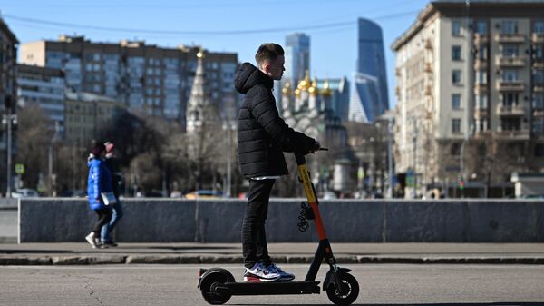 Молодой человек едет на электросамокате в Москве