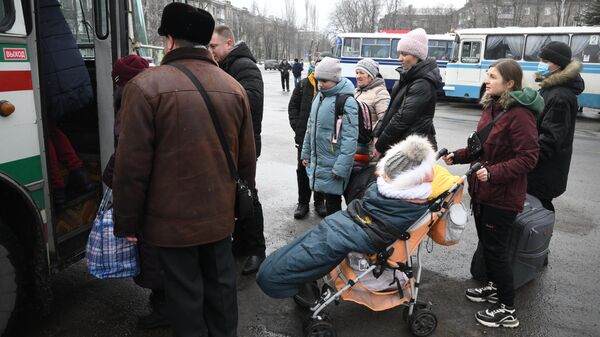 Люди с детьми стоят возле автобуса во время эвакуации из Горловки на территорию России