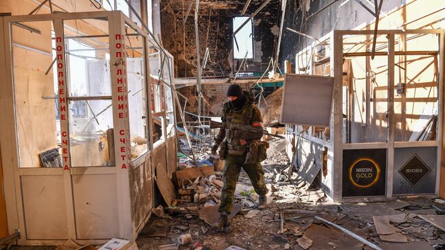 Военнослужащий ДНР осматривает разрушенное здание в Волновахе