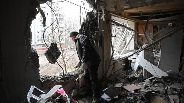 Мужчина в квартире, разрушенной в результате прямого попадания снаряда в жилой дом в Горловке