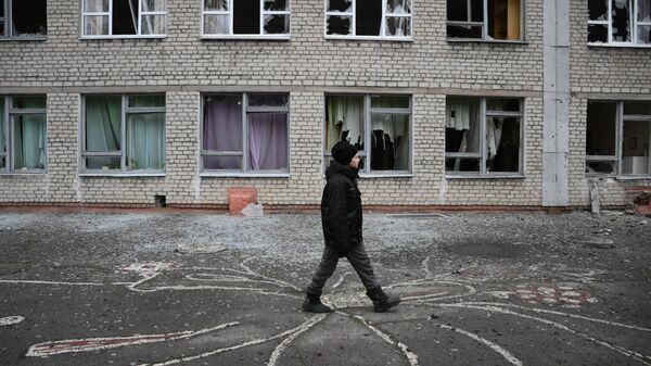 Подросток у здания школы в Горловке, поврежденного в результате обстрела ВСУ