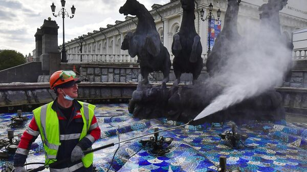 Сотрудник коммунальных служб моет фонтан на Манежной площади в Москве