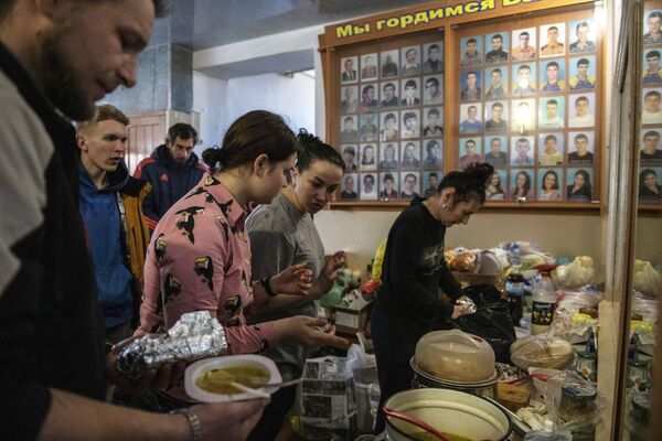 Люди разбирают продукты в центре размещения беженцев, расположенном в здании детско-юношеской спортивной школы в Старобельске