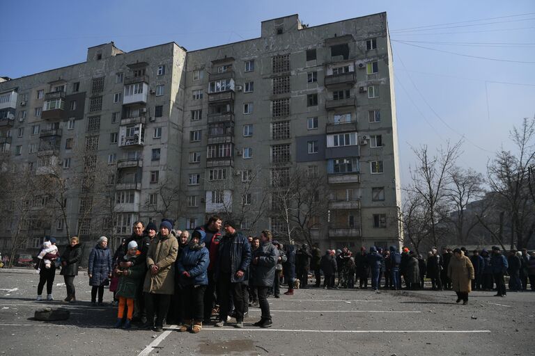 Жители Мариуполя стоят в очереди, чтобы получить гуманитарную помощь, доставленную из России