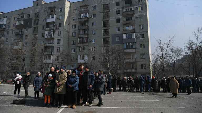 Жители Мариуполя стоят в очереди, чтобы получить гуманитарную помощь, доставленную из России