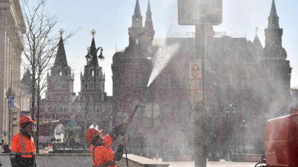 Сотрудники коммунальной службы моют дорожный знак на Тверской улице в Москве