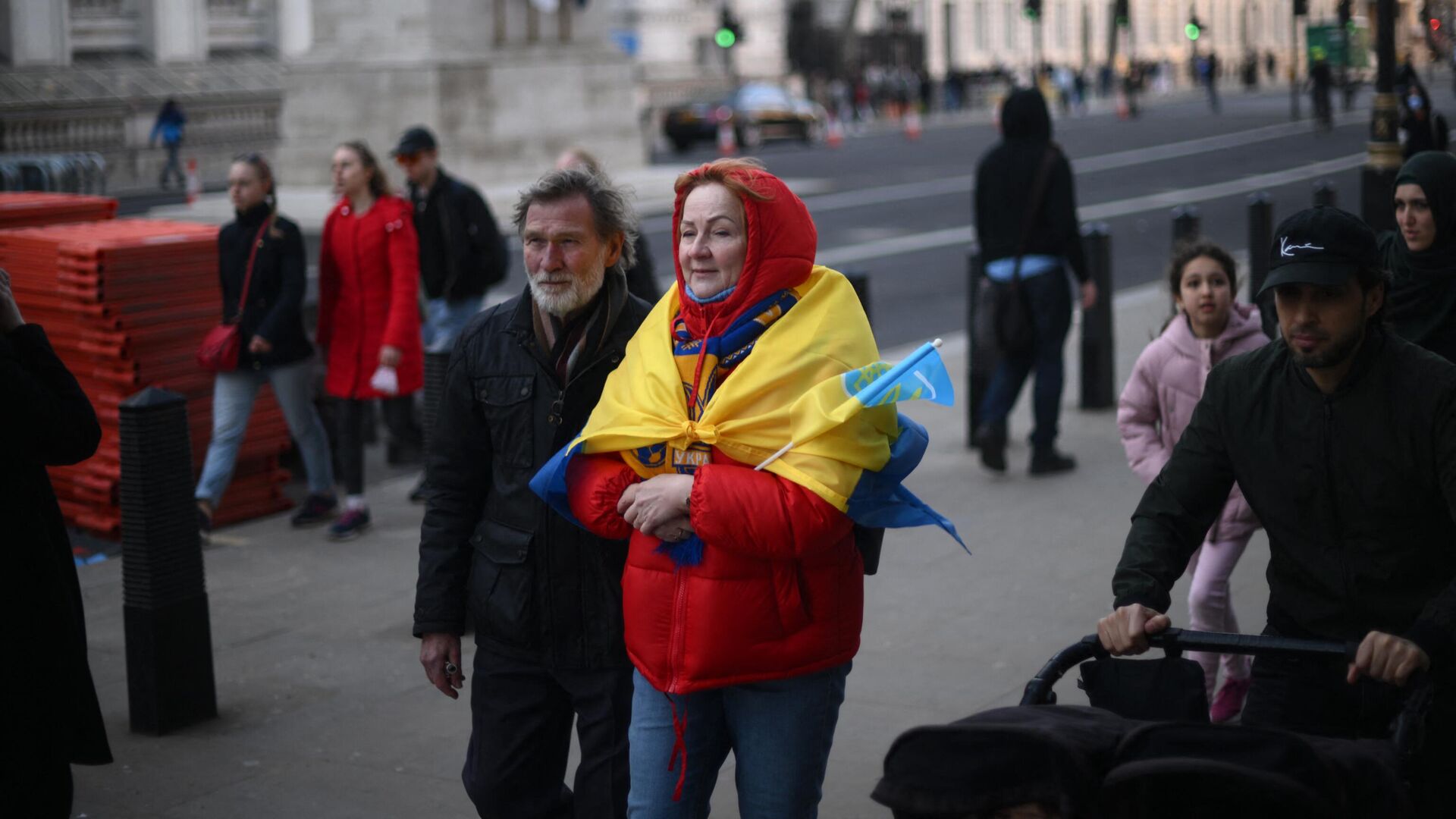 Женщина с флагом Украины, накинутом на плечи, идет по улице в Лондоне  - РИА Новости, 1920, 24.03.2022