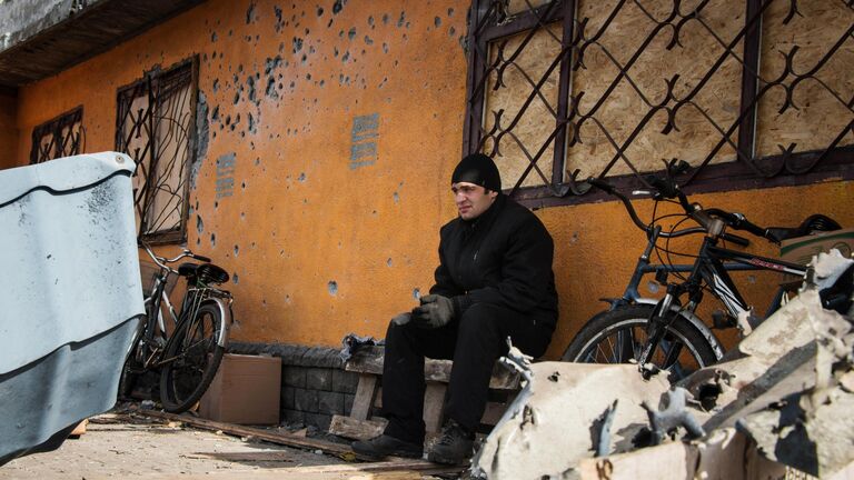 Житель Дебальцево у поврежденного в результате обстрела здания. Джон Траст / РИА Новости