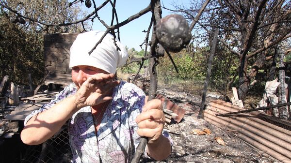 Женщина возле обгорелой яблони в поселке Зайцево города Горловка Донецкой области после обстрела украинскими силовиками