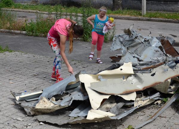 Дети осматривают обшивку здания, пострадавшего в результате обстрела Киевского района Донецка.