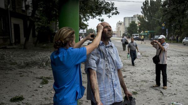 Врач оказывает помощь пострадавшему от артиллерийского обстрела в Луганске. 