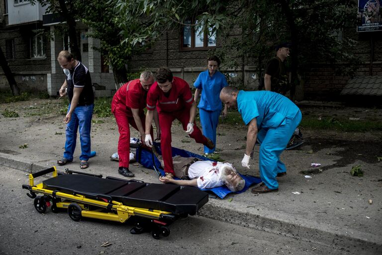 Врачи оказывают помощь раненному во время артиллерийского обстрела в Луганске.