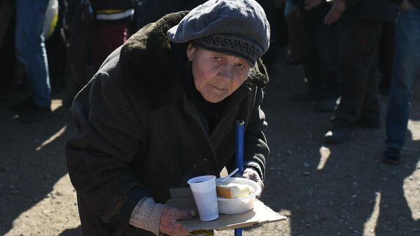 Пожилая беженка из Мариуполя в очереди за горячей едой в пункте временного размещения, организованном МЧС ДНР в селе Безыменное
