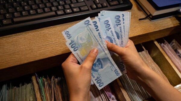 Работник пункта обмена валюты пересчитывает банкноты в турецких лирах 