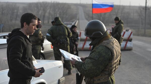Боец Народной милиции ДНР проверяет документы у водителя на блок-посту под Мариуполем