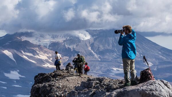 Туристы смотрят на вулкан Мутновский с вершины вулкана Горелого