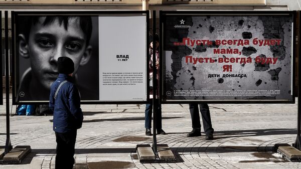 Мальчик возле одной из фотографий на выставке Пусть всегда будет мама, пусть всегда буду Я! Дети Донбасса на Большой Морской улице в Санкт-Петербурге