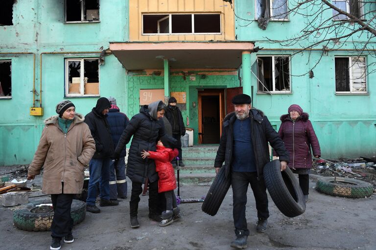 Жители во дворе разрушенного в результате обстрелов жилого дома в Мариуполе