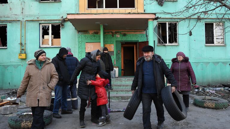 Жители во дворе разрушенного в результате обстрелов жилого дома в Мариуполе