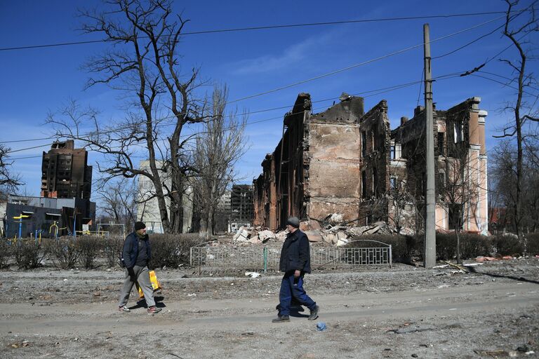 Жители города у разрушенного в результате обстрелов жилого дома в Мариуполе