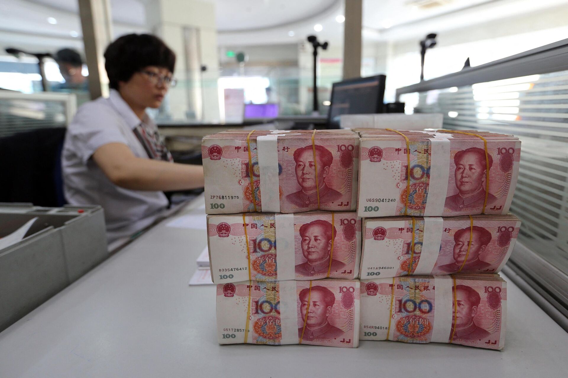 Банкноты юаня лежат на столе сотрудника банка в Ляньюньгане, Китай - РИА Новости, 1920, 29.03.2022