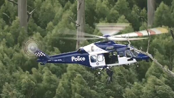 Полицейский вертолет во время поисково-спасательной операции на месте крушения вертолета в штате Виктория Австралия. Кадр из видео