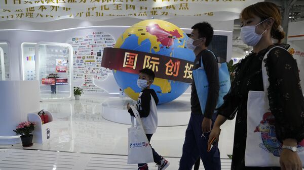 Посетители Китайской международной выставки проходят мимо глобуса с изображением зоны торгового оборота Китая 