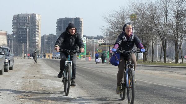 Мужчина с женщиной едут на велосипедах по улице в Мариуполе
