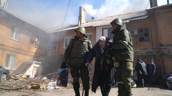 Военнослужащие ДНР помогают женщине эвакуироваться из дома, разрушенного в результате обстрелов в Мариуполе