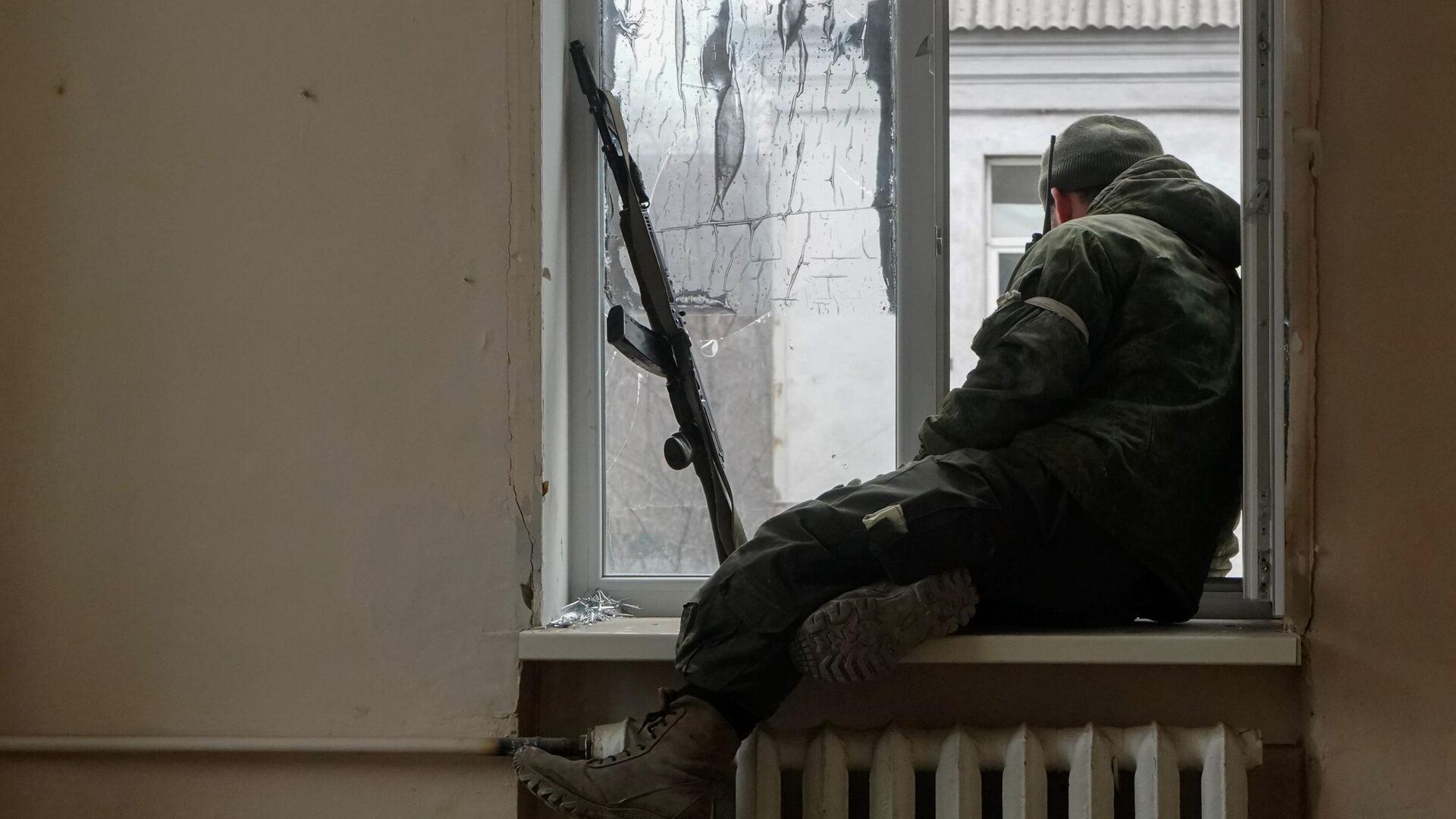 Военнослужащий ДНР сидит у окна во время боестолкновений в Левобережном районе Мариуполя - РИА Новости, 1920, 04.04.2022