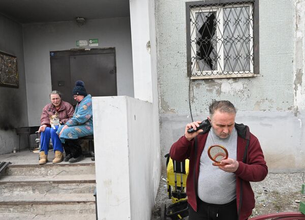 Мужчина бреется во дворе разрушенного дома в Мариуполе
