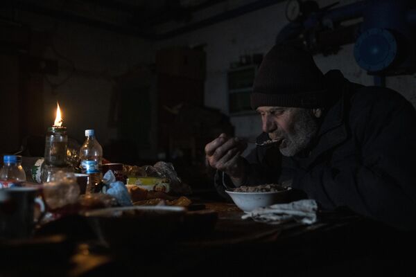 Мужчина принимает пищу в подвале дома в городе Рубежное Луганской области.