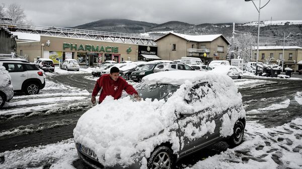 Мужчина чистит свой автомобиль после апрельского снегопада в Сент-Этьене, Франция 