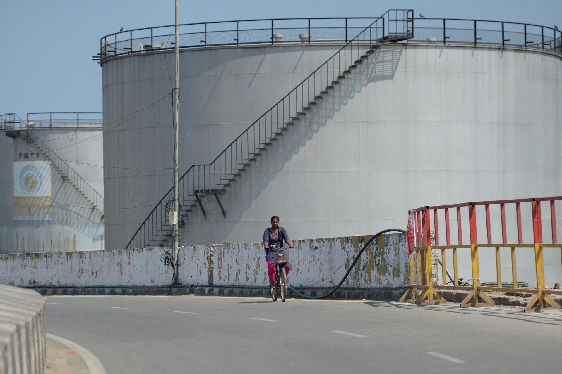 Девушка проезжает мимо нефтехранилища в Ченнаи, Индия  - РИА Новости, 1920, 07.04.2022