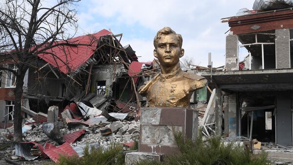Памятник герою Великой Отечественной войны Петру Шевченко на фоне разрушенных зданий в поселке Смоляниново в ЛНР