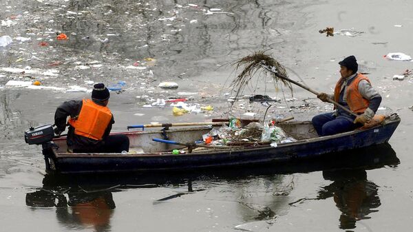 Рабочие собирают мусор, сброшенный в канал в Пекине 