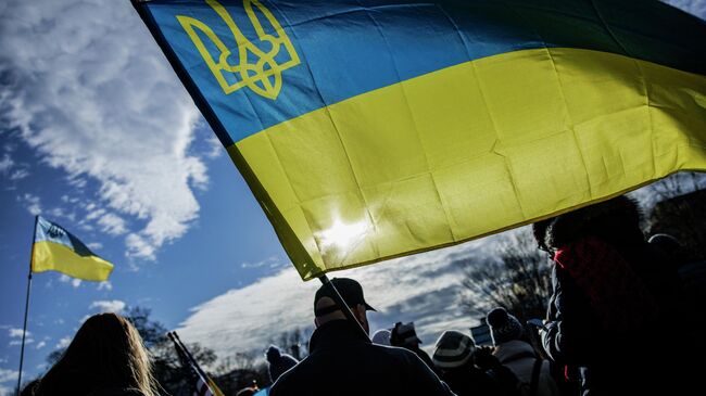 Люди держат украинские флаги во время митинга в поддержку Украины на Пенсильвания-авеню перед Белым домом в США