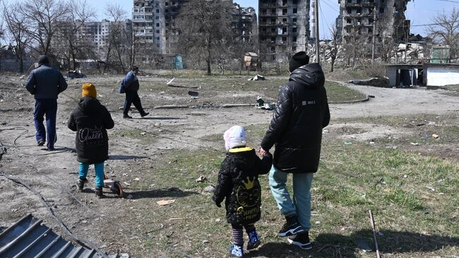 Люди идут с детьми по улице в Левобережном районе Мариуполя