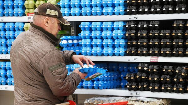 Покупатель выбирает куриные яйца в супермаркета Ашан Сити 