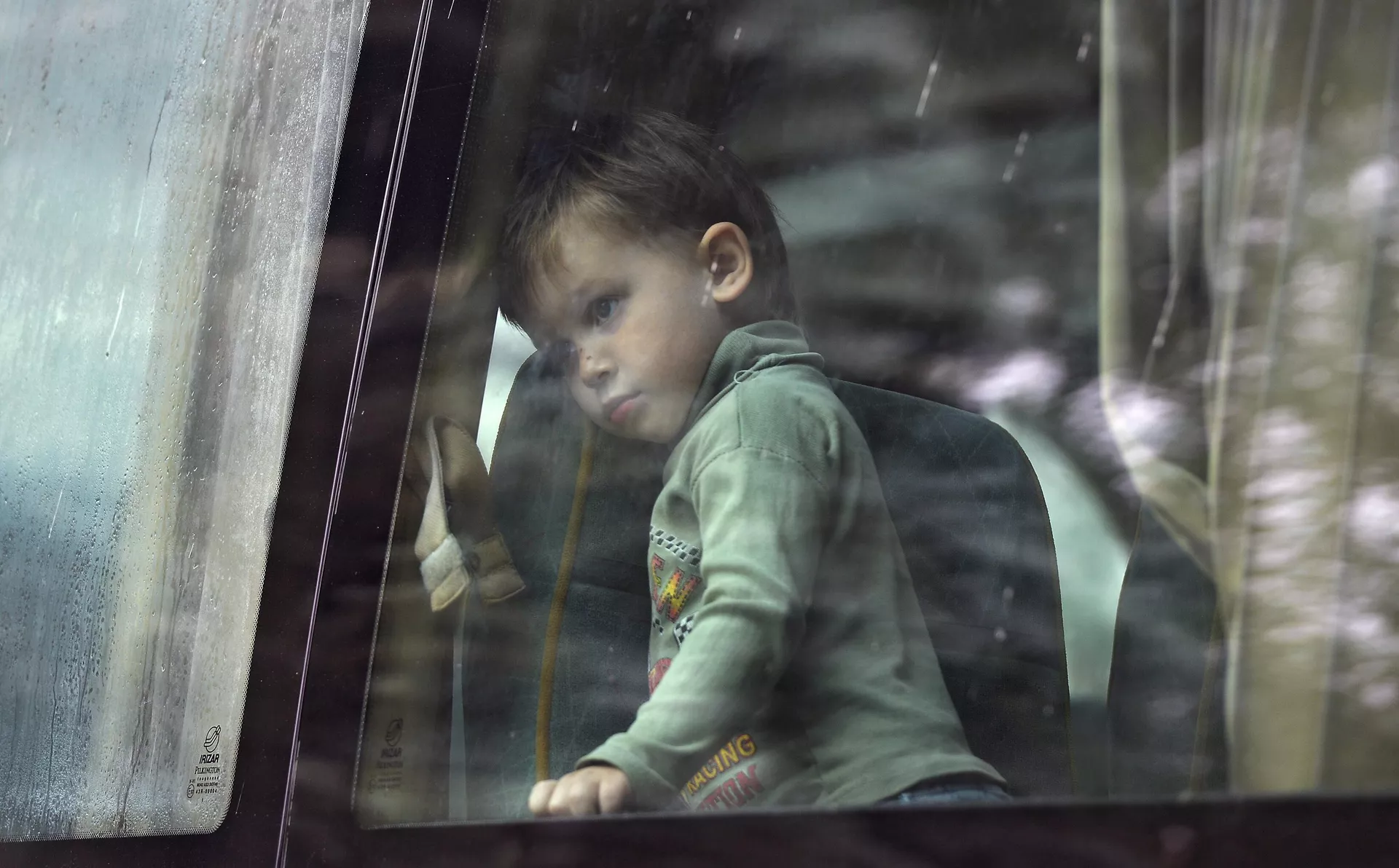 Девочка смотрит в окно автобуса перед отправкой из Славянска